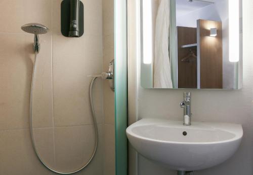 La salle de bains est pourvue d'un lavabo et d'une douche avec un miroir. dans l'établissement B&B HOTEL Fréjus Roquebrune-sur-Argens, à Roquebrune-sur Argens