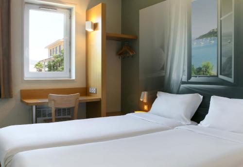 a hotel room with two beds and a window at B&B HOTEL Fréjus Roquebrune-sur-Argens in Roquebrune-sur-Argens