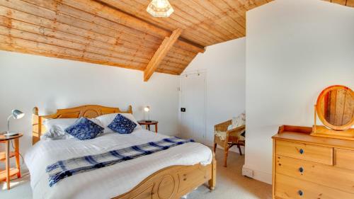 a bedroom with a bed and a wooden ceiling at West End Cottage in Llangennith