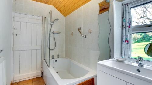 a bathroom with a tub and a shower and a sink at West End Cottage in Llangennith