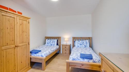 two twin beds in a room with a cabinet at Bluebell Cottage in Penclawdd
