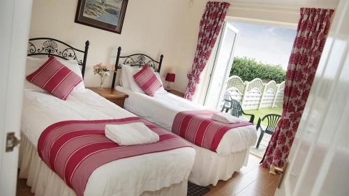 een slaapkamer met 2 bedden en een raam met uitzicht bij Clover Cottage in Port-Eynon