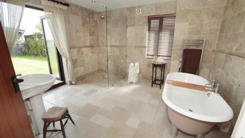 ein Bad mit einer Badewanne, einem Waschbecken und einer Dusche in der Unterkunft Driftwood House in Parkmill