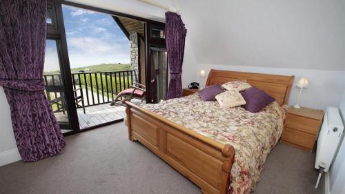 a bedroom with a bed and a balcony at Driftwood House in Parkmill