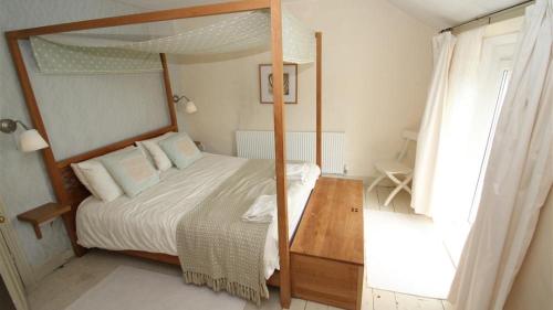 een slaapkamer met een hemelbed en een houten tafel bij Periwinkle Cottage in The Mumbles