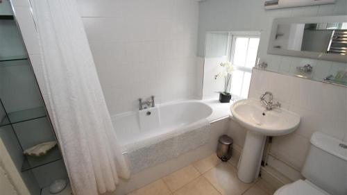 een witte badkamer met een bad en een wastafel bij Periwinkle Cottage in The Mumbles