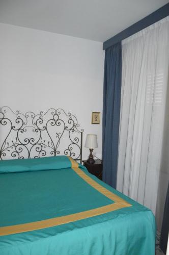 um quarto com uma cama com lençóis azuis e uma janela em SEI A CAPRI em Capri