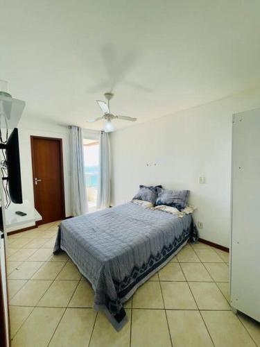 een slaapkamer met een bed en een plafondventilator bij 2 Quartos Frente Mar em Itapuã in Vila Velha