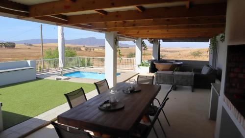 une terrasse avec une table, des chaises et une piscine dans l'établissement Bella Vista at Village-Living, à Koringberg