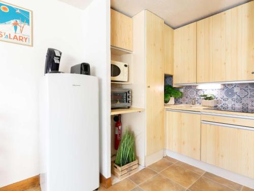une cuisine avec des armoires en bois et un réfrigérateur dans l'établissement Duplex pour 4 pers. avec balcon, proche centre et téléphérique, parking & casier à skis - FR-1-296-128, à Saint-Lary-Soulan