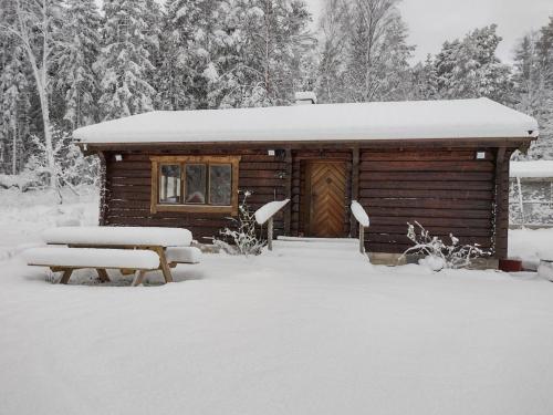 a log cabin in the snow with a bench at Charmig stuga mitt i naturen! in Upplands-Väsby