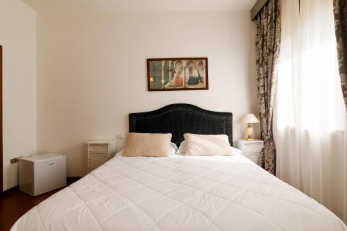 a bedroom with a large white bed and a window at Agriturismo Villa Godenano - Pool&Restaurant in Castellina in Chianti