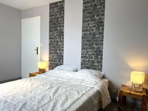 een slaapkamer met een bed en een bakstenen muur bij Maison Saint-Gilles-Croix-de-Vie, 4 pièces, 6 personnes - FR-1-224-750 in Saint-Gilles-Croix-de-Vie