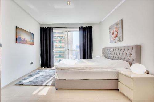 um quarto branco com uma cama e uma janela em New Stylish 1 BD in West Avenue Marina em Dubai