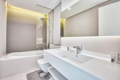 uma casa de banho branca com um lavatório e uma banheira em New Stylish 1 BD in West Avenue Marina em Dubai