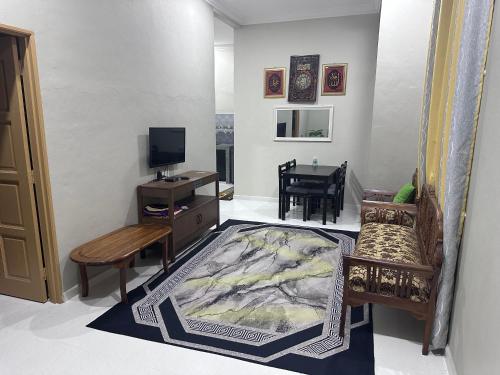 ein Wohnzimmer mit einem TV, einem Sofa und einem Tisch in der Unterkunft WAJA HOMESTAY in Kampong Pengkalan Nyireh