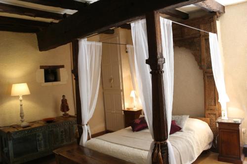 - une chambre avec un lit à baldaquin et des rideaux dans l'établissement La Gilbertie, à Allemans