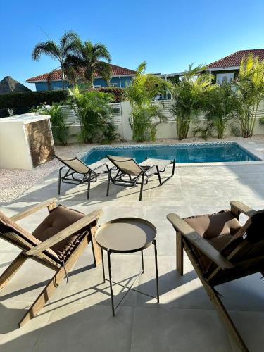 a patio with chairs and a table and a pool at Villa Vista Montaña in Willemstad