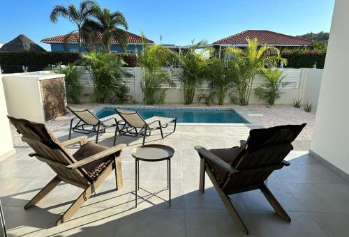 a patio with chairs and a table and a pool at Villa Vista Montaña in Willemstad