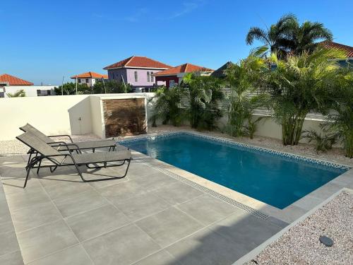 a swimming pool with a bench next to a house at Villa Vista Montaña in Willemstad