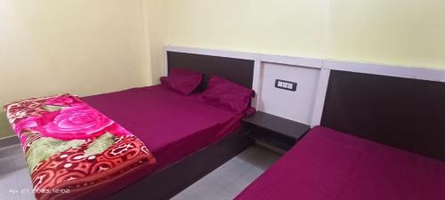 Schlafzimmer mit einem Bett mit lila Bettwäsche und rosa Kissen in der Unterkunft Badrinath Jbk by Prithvi Yatra Hotel in Badrīnāth