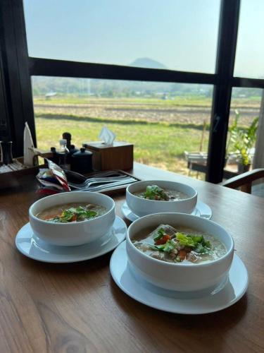 three bowls of soup sitting on a wooden table at The field@pua เดอะฟิลด์แอทปัว in Pua