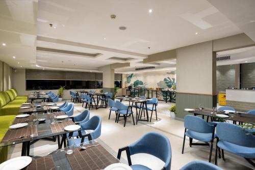 a restaurant with long tables and blue chairs at PRESIDENCY AIRPORT HOTEL in Cochin