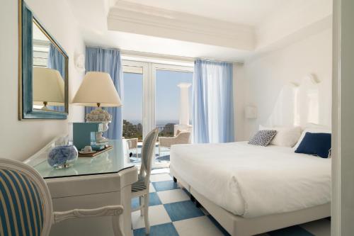 a bedroom with a bed and a desk with a glass table at La Residenza Capri in Capri