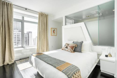 - une chambre avec un grand lit blanc et une fenêtre dans l'établissement Financial District 1br w WD gym elevator NYC-1362, à New York