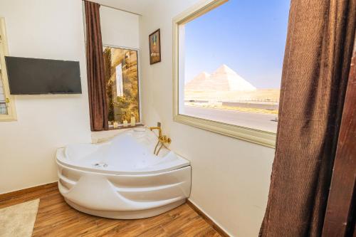 White Pyramids Inn في القاهرة: حمام مع نافذة كبيرة وحوض استحمام أبيض