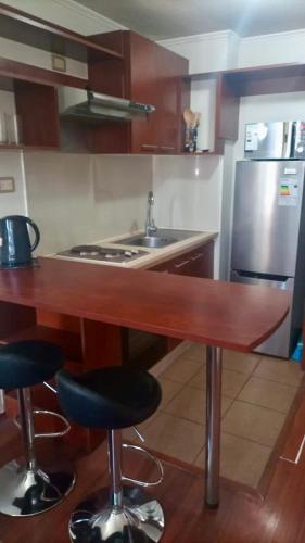 a kitchen with a counter with stools and a sink at Departamento Central Santiago in Santiago