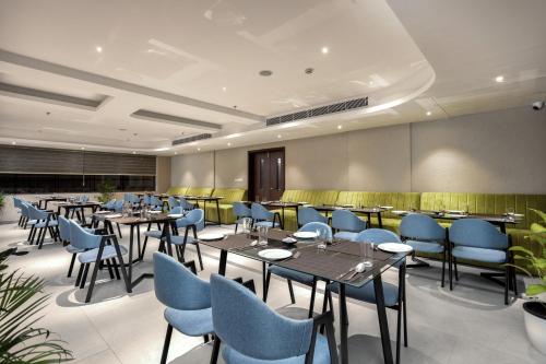a dining room with tables and blue chairs at PRESIDENCY AIRPORT HOTEL in Cochin