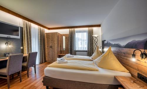 ein Hotelzimmer mit einem großen Bett und einem Schreibtisch in der Unterkunft König Ludwig Stub´n in Prien am Chiemsee