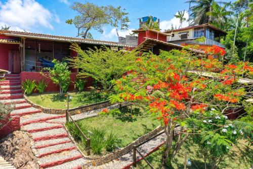 a house with red flowers in front of it at Pousada Pedra Alta in Itacaré