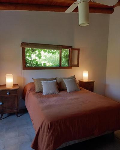 a bedroom with a bed with two night stands and a window at Casa.Colibri.LaCumbre in La Cumbre