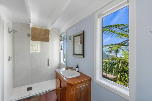 a bathroom with a sink and a window at Piha - City Escape, Piha Holiday Home in Piha