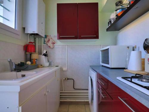 - une cuisine avec des placards rouges et blancs et un évier dans l'établissement Appartement lumineux à Royan - proche gare et plage, 6 pers., terrasse, animaux admis - FR-1-738-24, à Royan