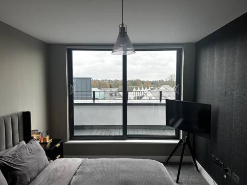 a bedroom with a bed and a large window at Luxury Penthouse Apartment in Uxbridge