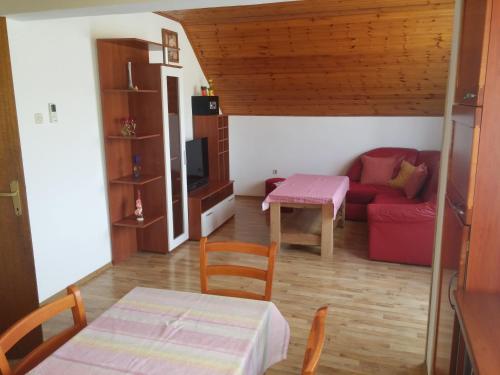 een woonkamer met een rode bank en een tafel bij Galeva apartman in Smoljanac