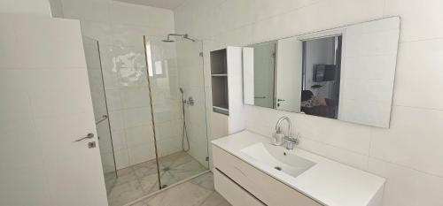 La salle de bains blanche est pourvue d'un lavabo et d'une douche. dans l'établissement Villa Royal Comfort - Top Holiday Resort Heated Pool & Jucuzzi רק למשפחות, à Eilat