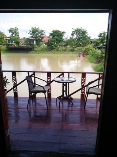 a porch with two chairs and a table and a view of a river at Baan Suan Thanwalai Khon Kaen in Khon Kaen