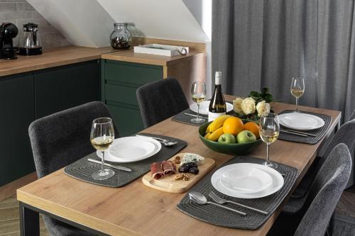a wooden table with glasses of wine and a bowl of fruit at 8th Hill Apartments in Plovdiv