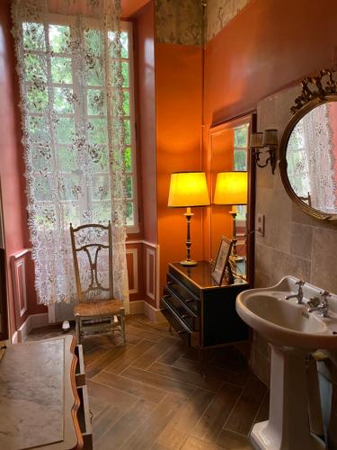 a bathroom with a sink and a mirror and a chair at Maison d'Hôtes de La Rivière in Pexiora