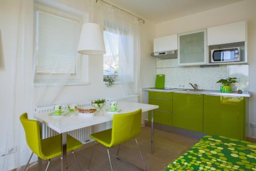 a kitchen with green cabinets and a white table and chairs at Apartment Zelená zahrada in Mladá Vožice