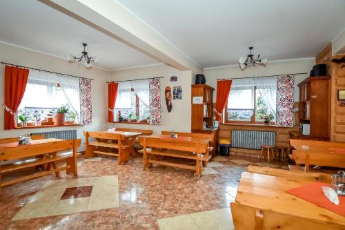 a dining room with wooden tables and windows at Cudzichówka in Biały Dunajec