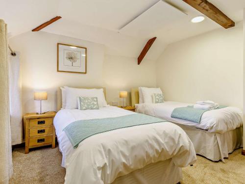 twee bedden in een kleine kamer met twee lampen bij 3 Bed in Umberleigh 65851 in Atherington