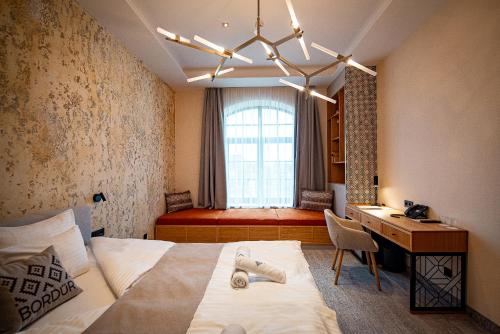 1 dormitorio con cama, escritorio y ventana en Bordűr Wellness Hotel Superior és Szőnyegmúzeum, en Békésszentandrás
