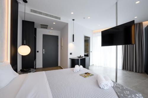 a bedroom with a white bed with a flat screen tv at EcoHeaven Suites in Amoudara Herakliou