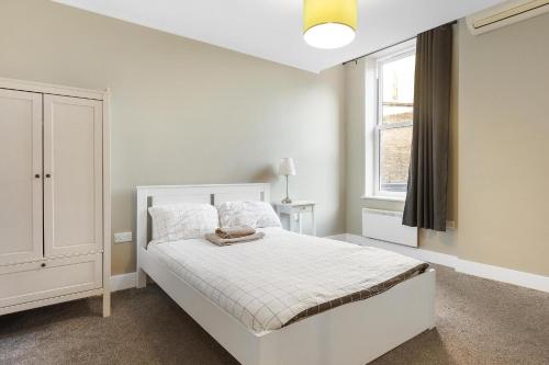 a white bedroom with a bed and a window at 221 Clapham Road Apartments in London