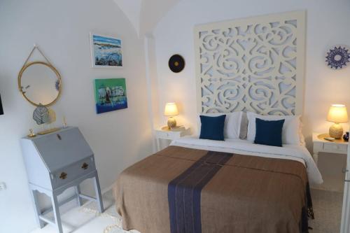 a white bedroom with a bed and a mirror at Dar AZUR HAMMAMET FORT in Hammamet